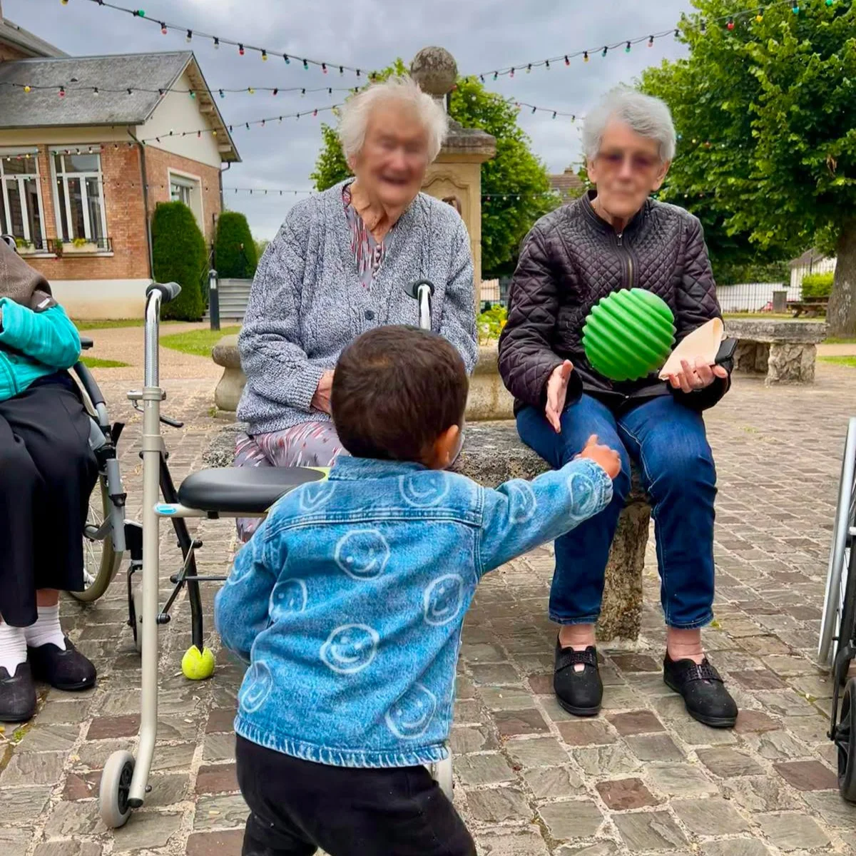 Des seniors de la Résidence Madeleine-Brès jouent au ballon avec un enfant du Relai petite enfance.