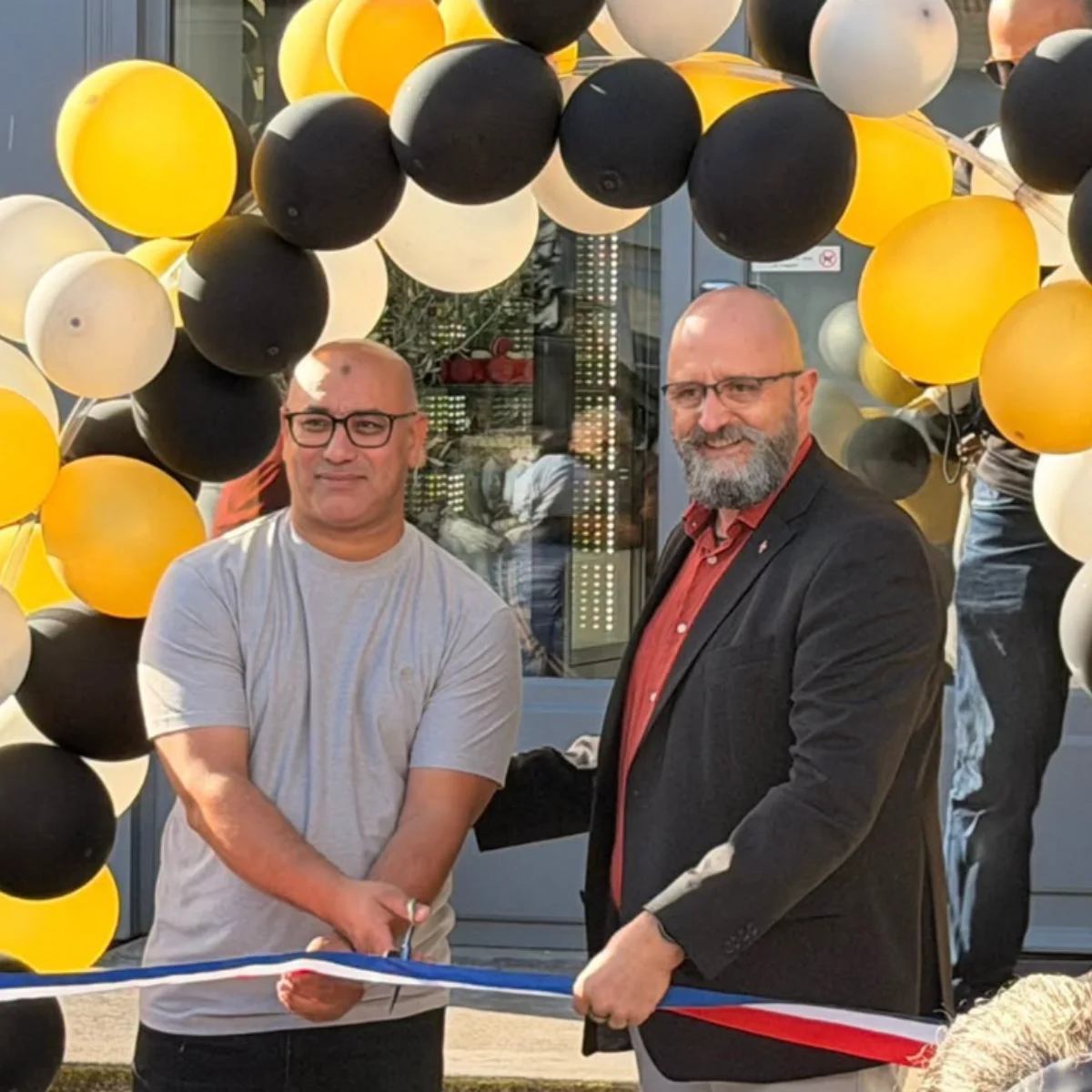 monsieur le Maire et le nouveau boulanger inaugurent la boulangerie en coupant un ruban tricolore 