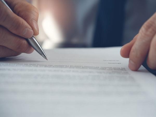 Une main supervisant un document avec la pointe de son stylo