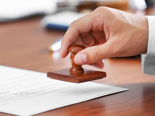 Une main tenant un tampon pour valider un document administratif