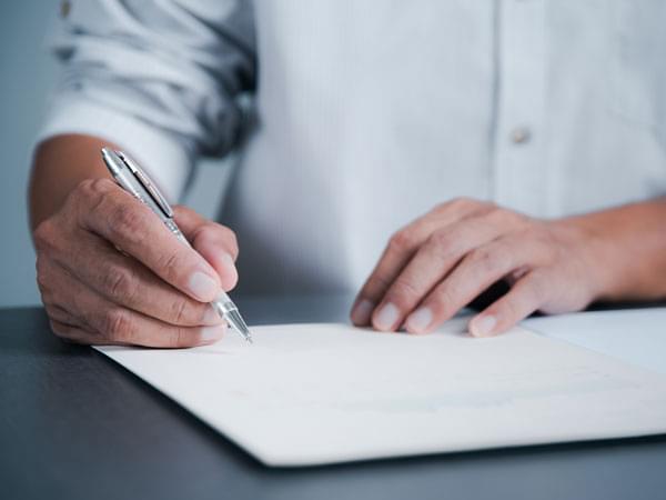 Une main signant un document avec un stylo