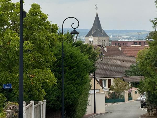 Photo d’une rue de la ville de Buchelay avec une vue du clocher de son église
