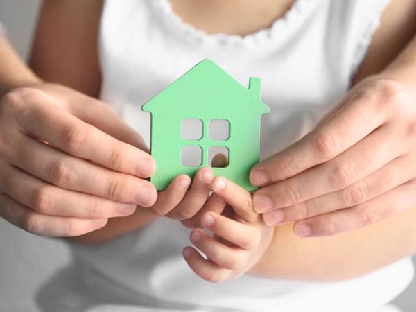 Les mains d’un enfant et d’un adulte tiennent un symbole de maison verte