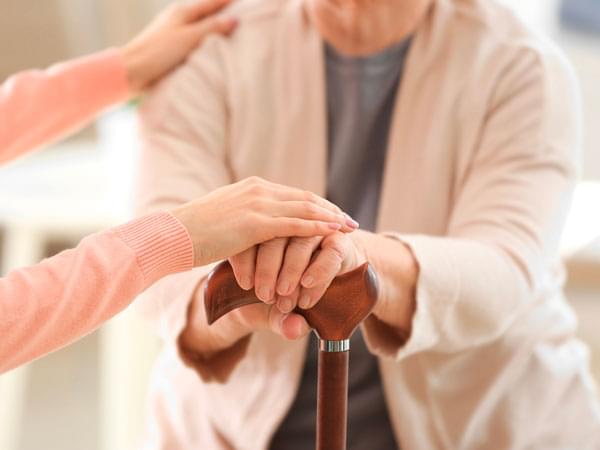 Une personne agée se tient sur une canne