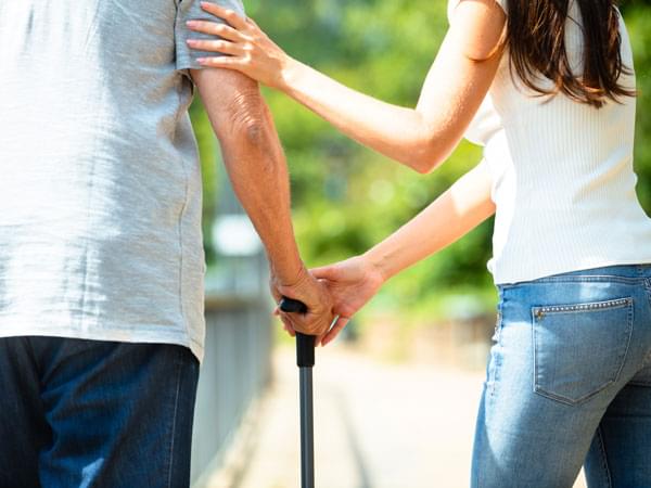 Une femme aide une personne à marcher avec une canne