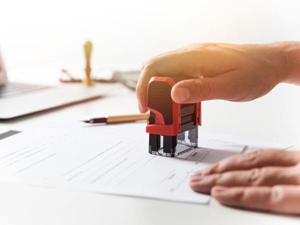 Une main tamponne une attestation d’accueil
