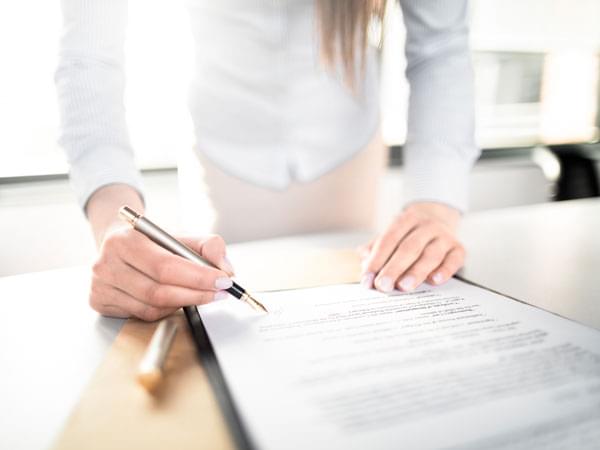 Une main signe un document de changement de nom 