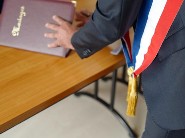 Maire avec son écharpe tricolore ouvrant le livret de Mariage officiel