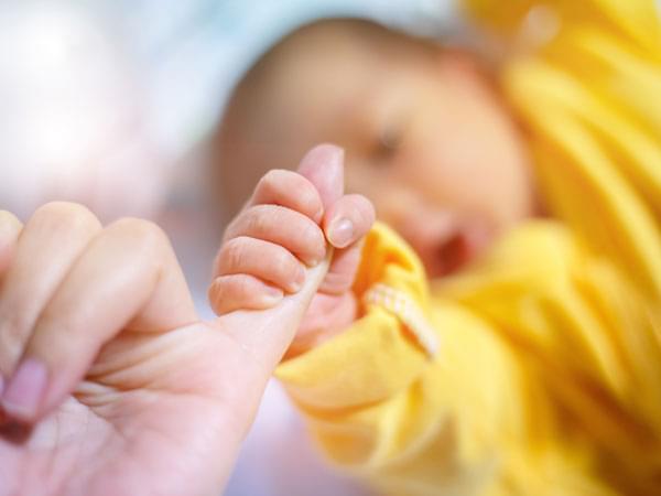 Bébé tenant le doigt d’un adulte
