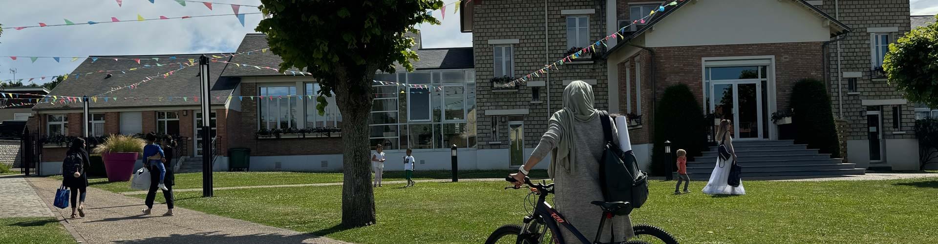 Femme de dos poussant un vélo dans le Parc de la Mairie de Buchelay